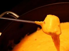 a ladle full of melted cheese being stirred