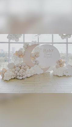 a baby shower is displayed in front of a window with balloons and flowers on it