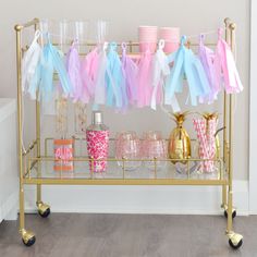 a gold bar cart with pink, blue and white decorations