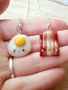 a hand holding two miniature food items in it's palm, one has an egg and the other has bacon