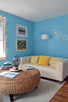 a living room with blue walls and wicker furniture in the corner, including a round coffee table