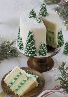 two pieces of cake sitting on plates next to each other with frosting and trees