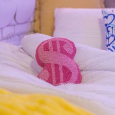 a pink stuffed animal sitting on top of a bed next to pillows and throw pillows