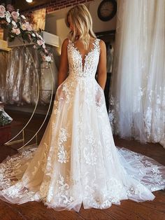 a woman in a white wedding dress looking at the back of her bridal gown