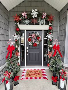 two christmas wreaths on the front door of a house decorated with red and white decorations