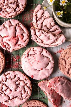 several cookies with pink icing sitting on a cooling rack