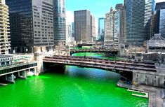 a river with green water in the middle of some tall buildings and bridge over it