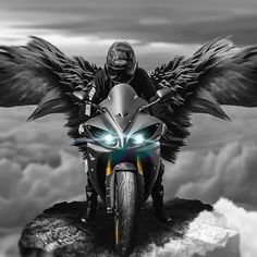 a man riding on the back of a motorcycle with wings flying over it's head