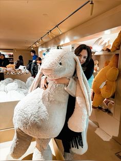 a woman is hugging a giant stuffed animal