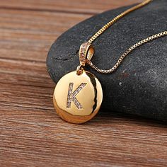 a gold necklace with the letter k on it and a diamond pendant attached to it