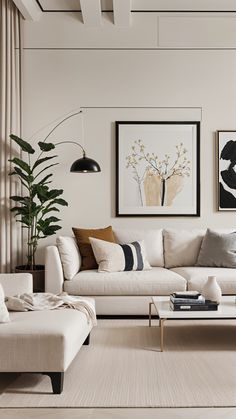 a living room filled with white furniture and paintings on the wall above it's windows