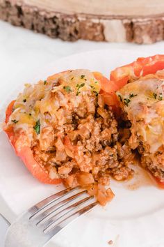 two stuffed peppers on a plate with a fork