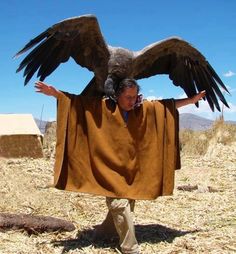 a man with an eagle on his shoulder in the middle of a desert area,