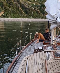 two people sitting on the deck of a sailboat