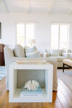 a living room filled with furniture and a white box on top of a wooden floor