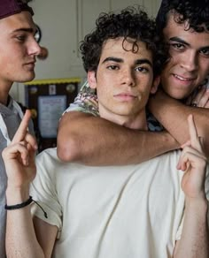 three young men standing next to each other with one holding the other's hand up