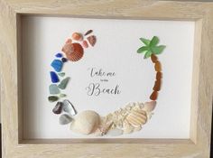 there is a frame with sea glass in the shape of a palm tree and seashells