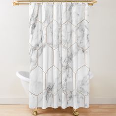 a shower curtain with white marble pattern and gold hardware on the bottom, hanging in a bathroom