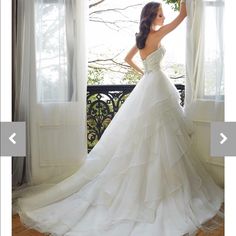 a woman in a wedding dress standing by a window