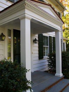 a white house with green shutters on the front porch