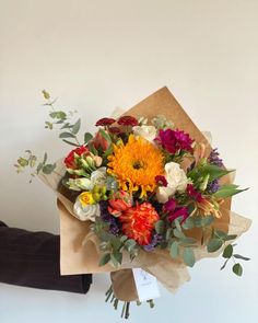 a bouquet of flowers sitting on top of a piece of paper next to a person's hand