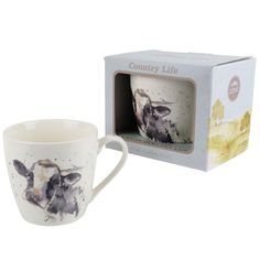 a coffee cup with an image of a cow on it in front of a box