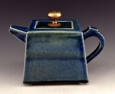 a blue teapot with a gold top on a white table