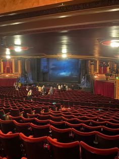 an empty theater with red seats and people