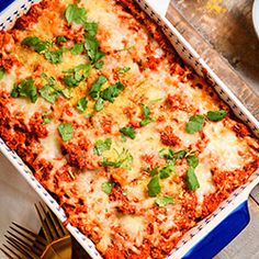 a casserole dish with meat, cheese and herbs in it on a wooden table