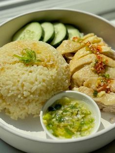 a white plate topped with rice and meat next to cucumbers