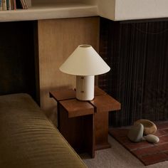 a lamp on a table next to a couch and bookshelf in a living room