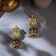 Introducing our Amara Mini Jhumkis – a blend of tradition and modern elegance. These Indian jhumka silver earrings feature pastel green stones in jadau craft on the studs, with a central polki. The jhumki showcases alternate polki and black stones in a captivating jadau style. Crafted in silver, gold-plated for a premium look, these chandi ka jhumka earrings redefine sophistication. Shop online for pearl jhumka earrings with kundan jadau polki design, embracing the allure of chandi ki earrings. Festive Fusion Kundan Jhumkas, Green Dual-tone Chandbali Jewelry, Elegant Green Jhumkas For Festive Occasions, Festive Green Fusion Style Jhumkas, Elegant Green Festive Jhumkas, Festive Dual-tone Kundan Chandbalis, Fusion Style Chandbali Jhumkas With Cutdana, Elegant Green Kundan Jhumkas, Green Jhumkas For Navratri