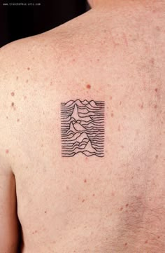 a man with a tattoo on his back that has mountains and waves in the water