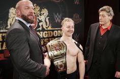 two men standing next to each other in front of a sign with the word kingdom wrestling on it