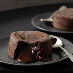 two plates with chocolate desserts on them and one has a spoon in the middle