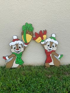 two cartoon bears are standing in the grass with christmas hats and scarfs on their heads