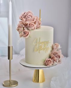 a white cake with pink flowers on top and a candle next to it that says happy birthday