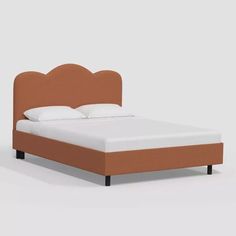 a bed with an orange headboard and white sheets on it's sides, in front of a gray background