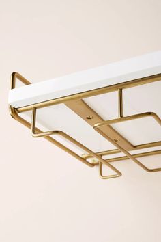 a white and gold shelf with two hooks on it