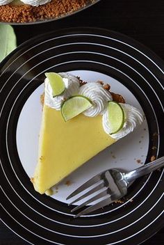 a slice of key lime pie on a black and white plate with a silver fork