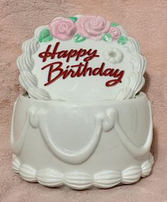 a birthday cake with pink roses on it sitting in a white container that says happy birthday