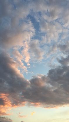 the airplane is flying high in the sky with clouds above it and another plane on the ground below