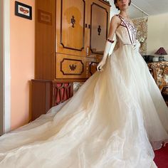 a woman in a white wedding dress standing next to a dresser and armoires