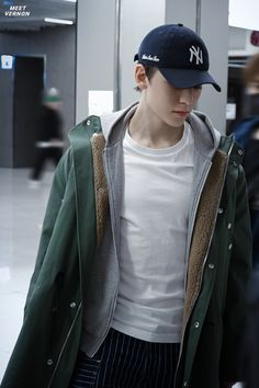 a young man wearing a new york yankees hat and green jacket in an airport terminal