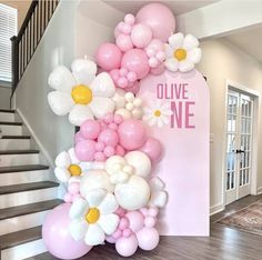 the balloon arch is decorated with white, pink and yellow balloons that spell out live one