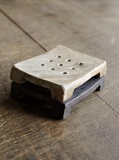 a small stone object sitting on top of a wooden floor with holes in the middle