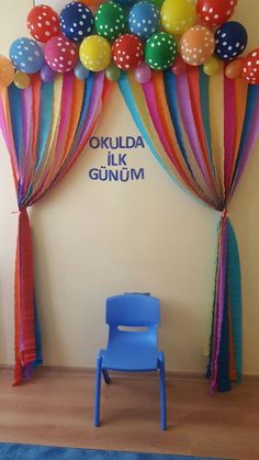 a blue chair sitting in front of a wall with balloons on it and a sign that says okula milk gum