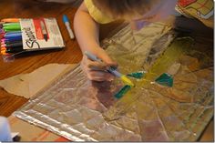 a young child is painting on tinfoil with crayons and colored pencils