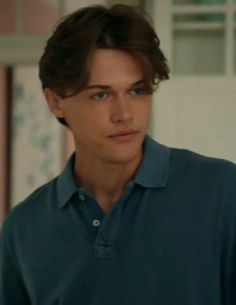 the young man is wearing a blue shirt and looking at something in front of him