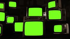 several televisions with green screen in the dark